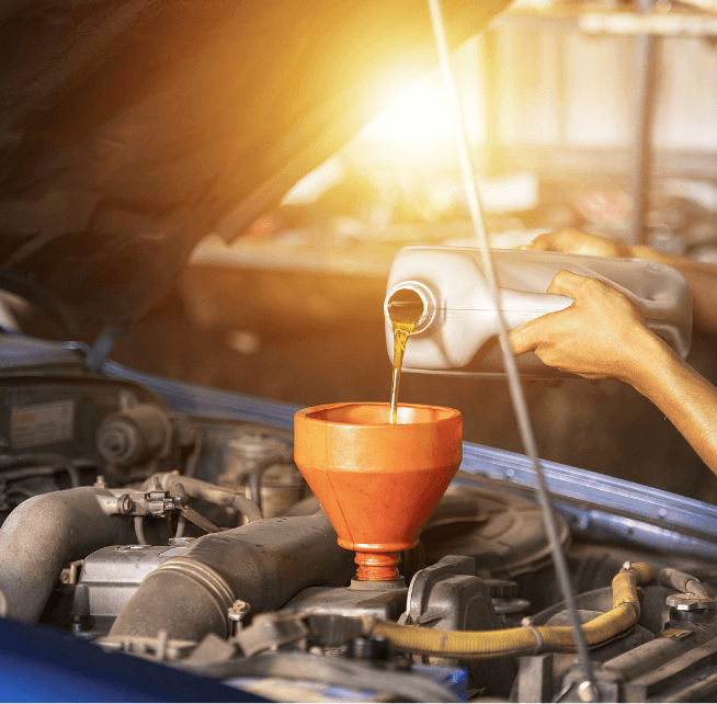 Image of a man pouring oil into an engine. Concept image of Branch Automotive's oil change services.