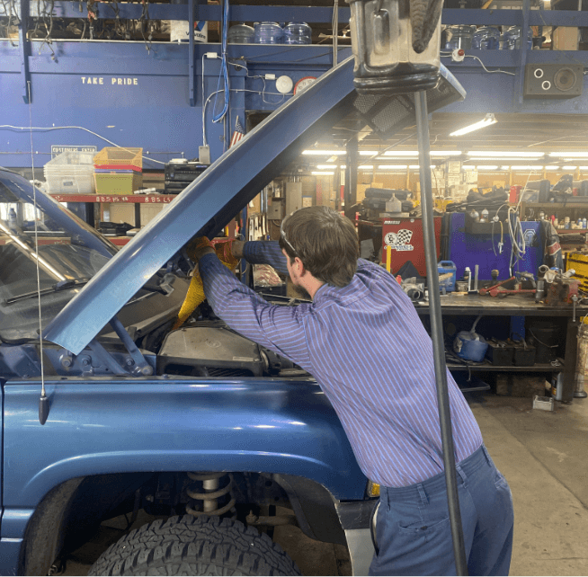 Image of a Branch Automotive mechanic performing preventative maintenance on a diesel truck.