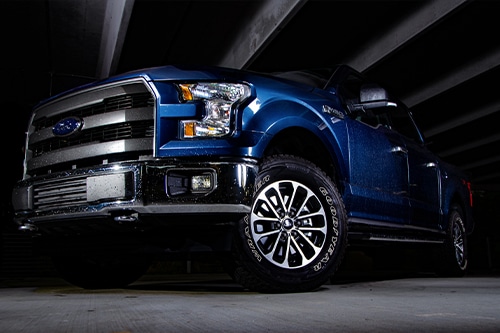 Ford F150 isolated by light with black background in parking garage.
