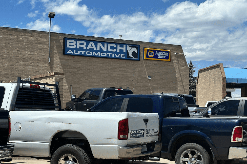 diesel service, diesel repair in Littleton, CO at Branch Automotive. Exterior view of Branch Automotive with multiple pickup trucks parked in front of the tan brick building.