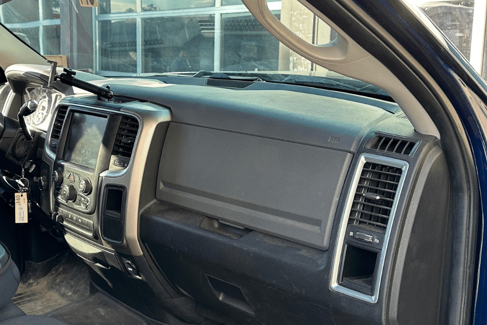 Interior view of a vehicle’s dashboard showing the infotainment system, climate control vents, and passenger-side airbag panel in a truck cabin. For diesel truck a/c repair in Littleton, CO, visit Branch Automotive.