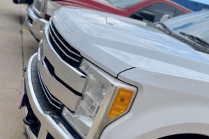 Powerstroke wrench light, diesel repair in Littleton, CO by Branch Automotive. Image of a white Ford Super Duty truck parked outside the shop, showcasing the front grille and headlight design—representing trusted diesel service and maintenance for Ford Powerstroke owners.
