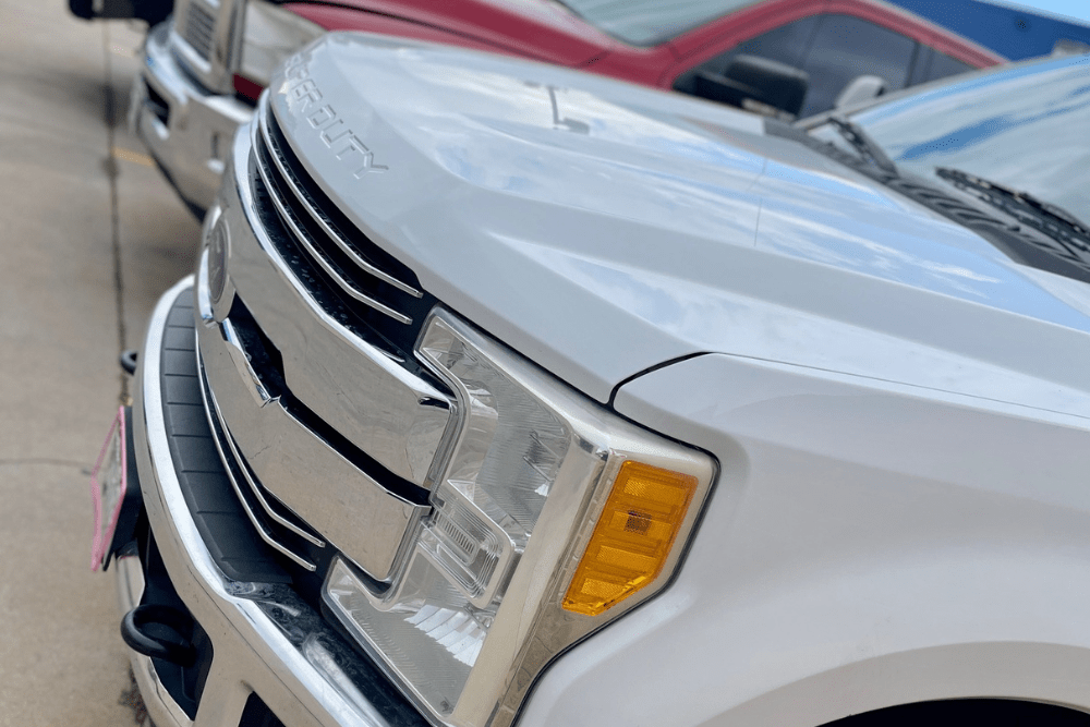 Powerstroke wrench light, diesel repair in Littleton, CO by Branch Automotive. Image of a white Ford Super Duty truck parked outside the shop, showcasing the front grille and headlight design—representing trusted diesel service and maintenance for Ford Powerstroke owners.