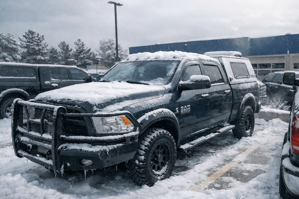 Diesel truck maintenance, diesel repair in Littleton, CO by Branch Automotive. Image of a snow-covered RAM 2500 parked in a snowy lot, highlighting harsh winter conditions that demand proper cold-weather maintenance, batteries, and diesel system checks.