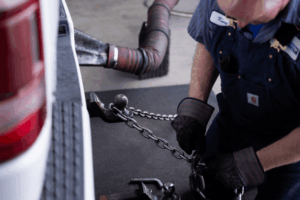Diesel emissions testing and repair in Littleton, CO by Branch Automotive. Image of a technician hooking safety chains to a truck’s trailer hitch, highlighting secure towing setup and professional accessory installation.