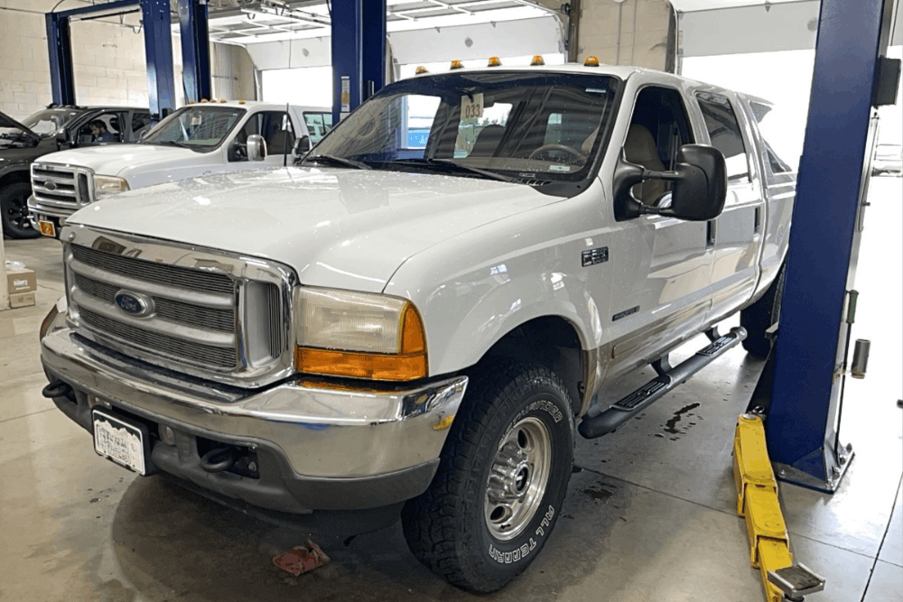 6.7L Powerstroke, diesel repair in Littleton, CO by Branch Automotive. Image of a white Ford Super Duty pickup inside the shop on a lift, ready for service and maintenance by professional diesel technicians.