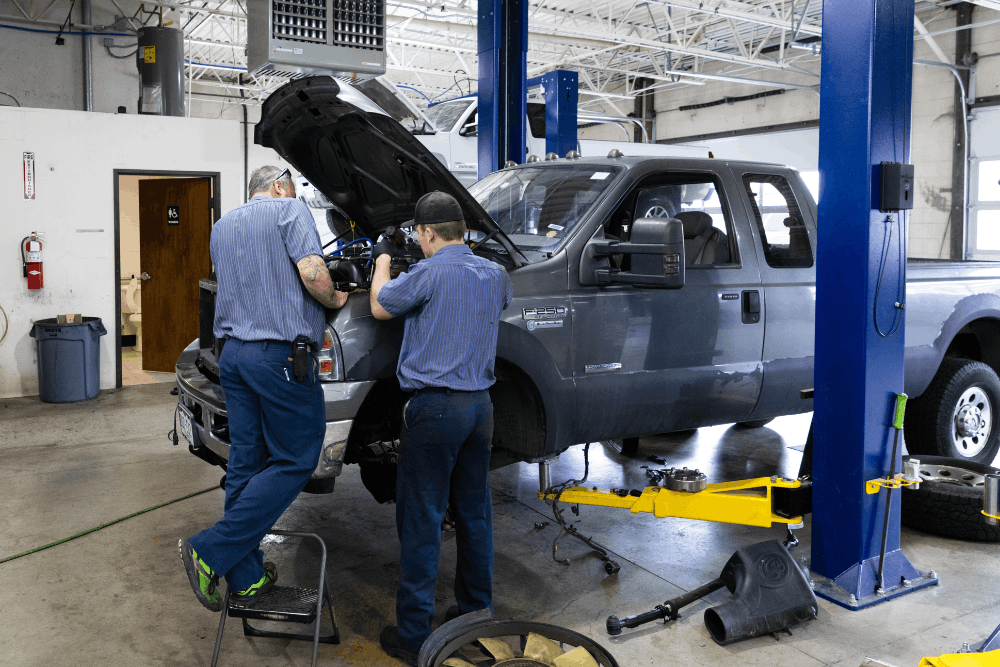 Diesel repair near Lone Tree, CO by Branch Automotive. Image of technicians inspecting and servicing a heavy-duty pickup truck on a lift, highlighting professional diesel diagnostics, engine repair, and maintenance.
