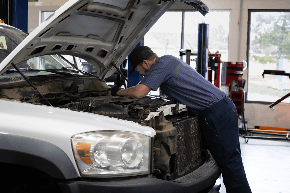 Diesel repair near Parker, CO by Branch Automotive. Image of a technician working under the hood of a diesel pickup in a professional repair shop, highlighting skilled diesel maintenance.