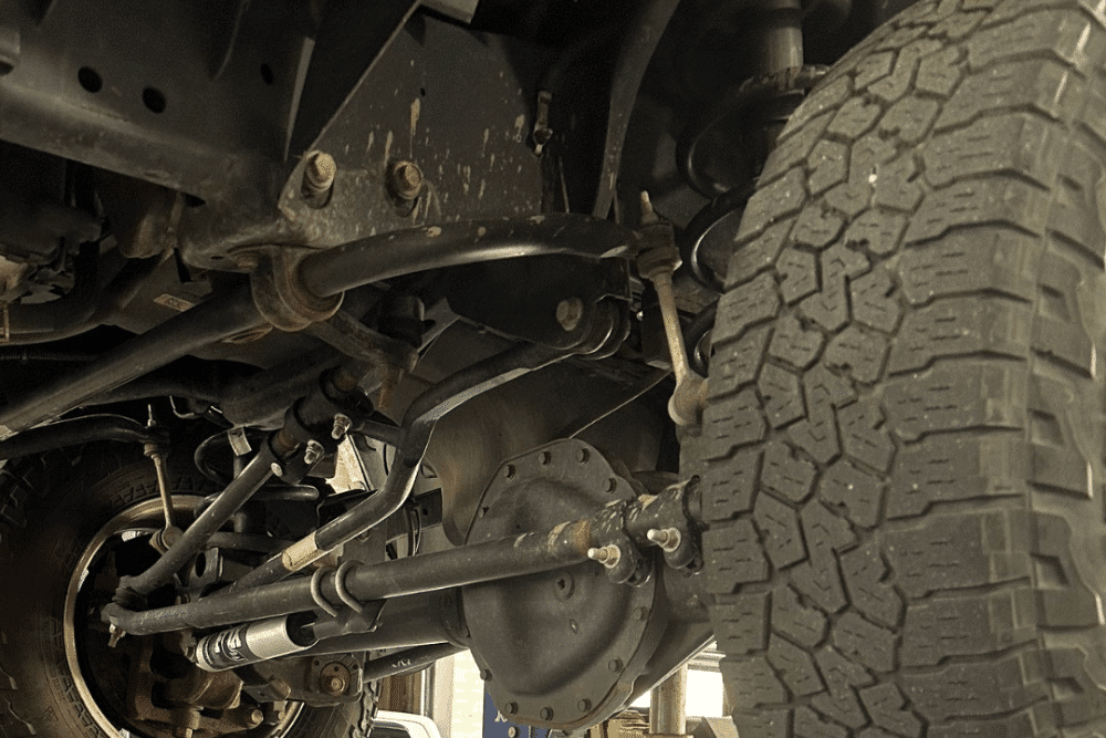 Steering & suspension repair in Littleton, CO by Branch Automotive. Image of truck undercarriage highlighting axle, control arms, and steering components, emphasizing precise diagnostics, durability, and improved ride stability for safe driving.